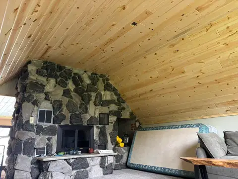 Spiral staircase beside stone fireplace and wooden ceiling in home